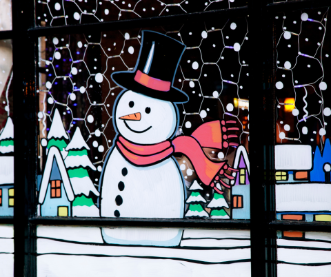 Window painted with a snowman with a red scarf and an winter scene