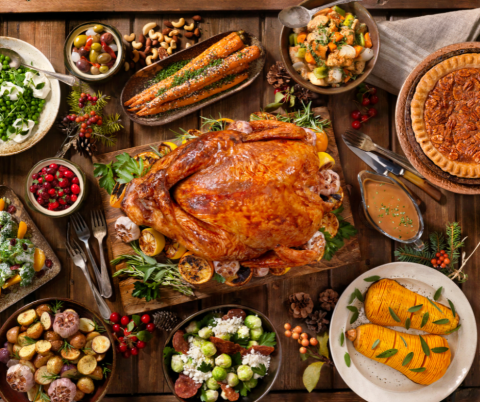 Table with a classic holiday meal including a roasted turkey, pecan pie, and side vegetable dishes.
