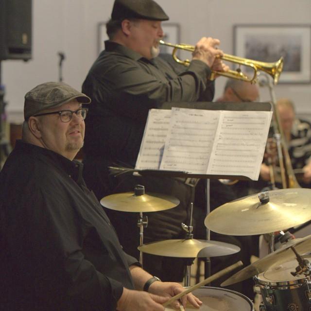 Two musicians with one on trumpet and one on drums.